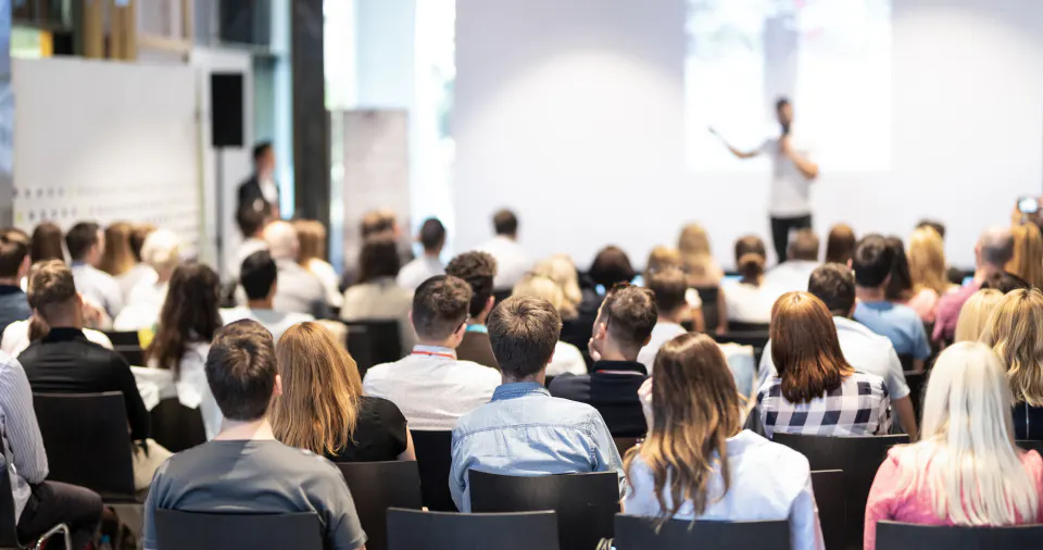 A large conference audience listening to a speaker.